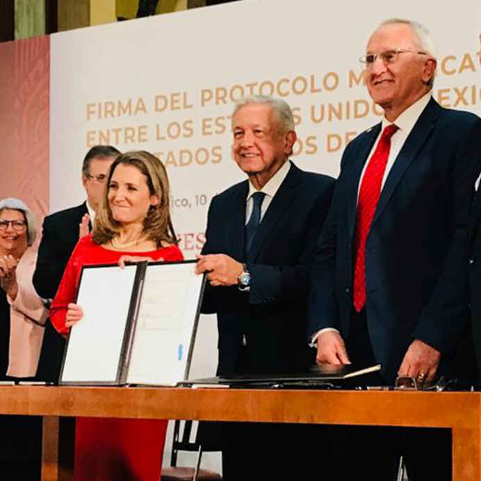 Chrystia Freeland holds the signed USMCA agreement alongside delegates from the U.S. and Mexico